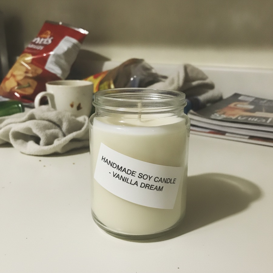 A phone photo of a candle on a cluttered desk